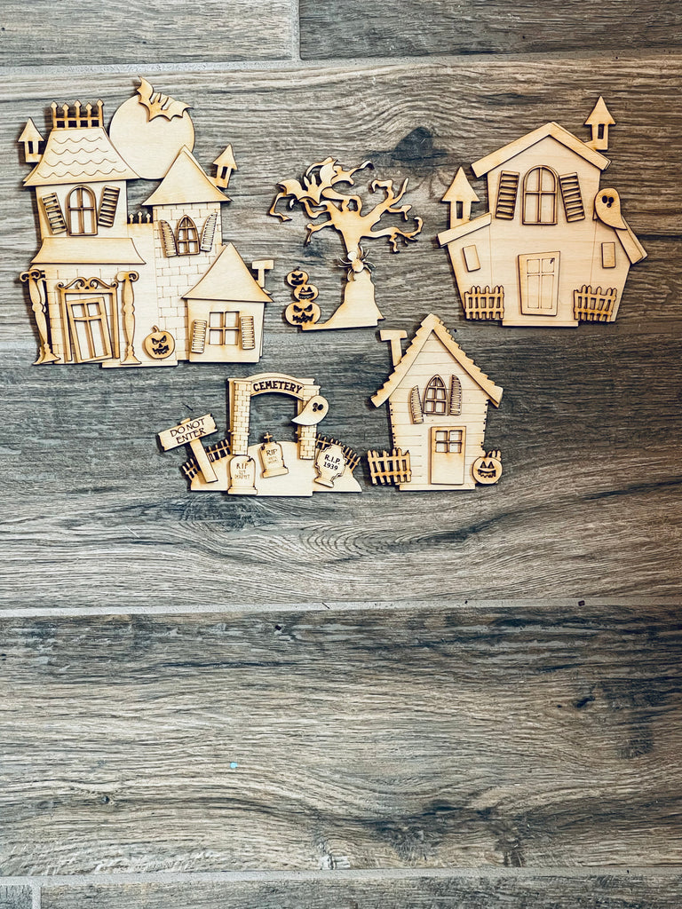 A set of DIY Halloween Village Standing Pieces - Haunted Village - Halloween Shelf Decor Blank Kit - Graveyard, Spooky House, Ghost Wood Blanks by Little August Ranch on a wooden floor.