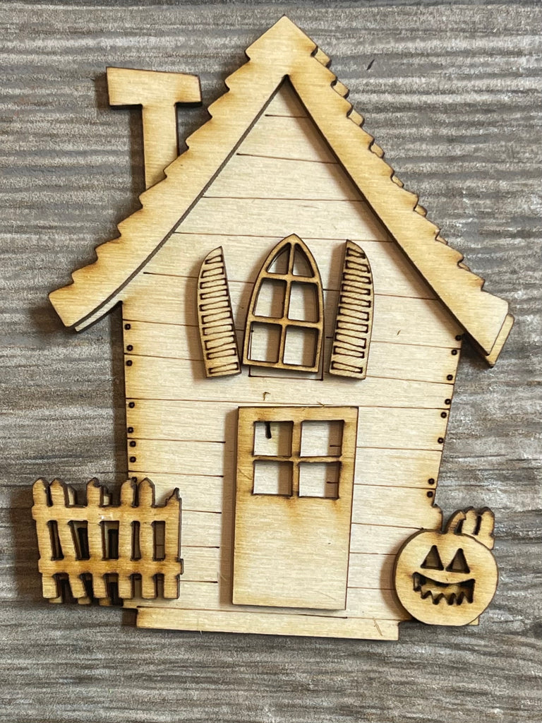 A Little August Ranch wooden house with a DIY Halloween Village Standing Pieces - Haunted Village - Halloween Shelf Decor Blank Kit - Graveyard, Spooky House, Ghost Wood Blanks pumpkin and a fence.