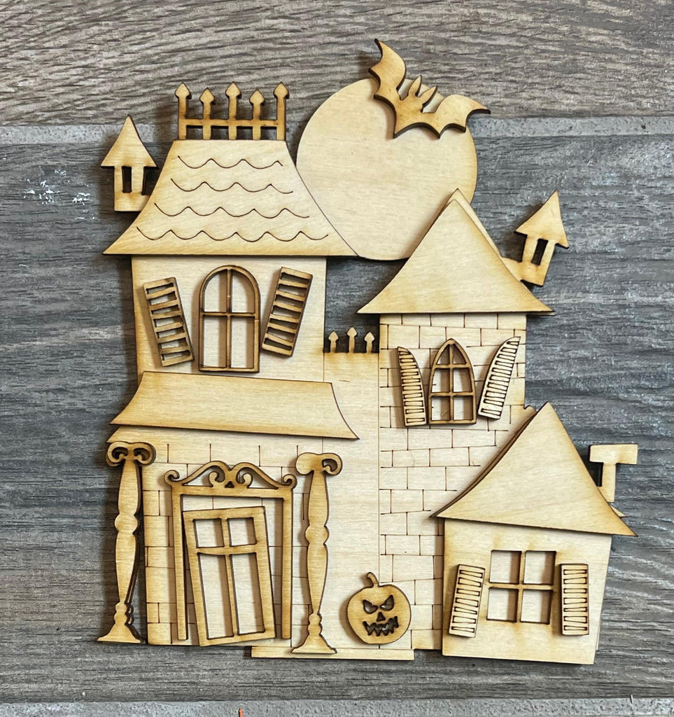 A wooden house with Little August Ranch&#39;s DIY Halloween Village Standing Pieces - Haunted Village - Halloween Shelf Decor Blank Kit - Graveyard, Spooky House, Ghost Wood Blanks on it.