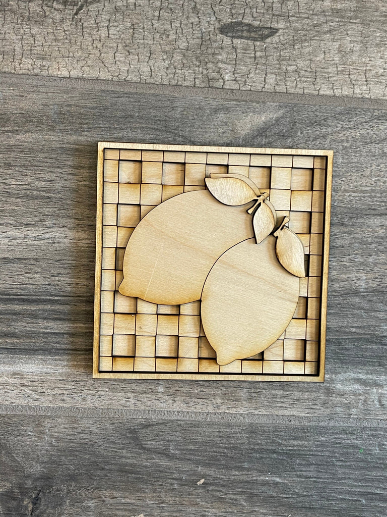 A wooden puzzle of a stylized Lemon Tiered Tray, consisting of multiple pieces fitting together within a square frame, displayed on a gray wood surface as part of a Little August Ranch Farmers Market Paint Kit.