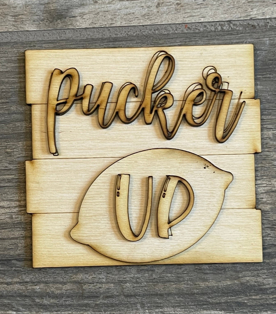 Wooden sign featuring the words &quot;Pucker Up&quot; with a stylized illustration of lips, crafted from layered wood pieces on a gray background, perfect for your Lemon Tiered Tray DIY Paint Kit by Little August Ranch.