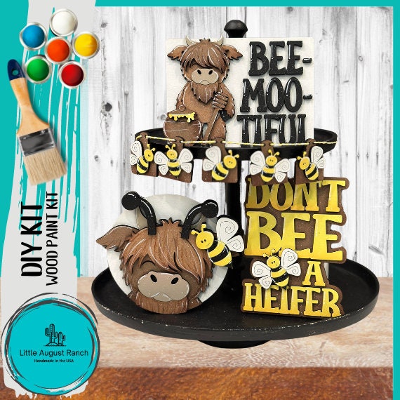 Craft painting set featuring the Little August Ranch Bee and Highland Cow Tiered Tray DIY Kit - Quick and Easy Tiered Tray Bundle with punny phrases &quot;bee-moo-tiful&quot; and &quot;don&#39;t bee a heifer&quot;.