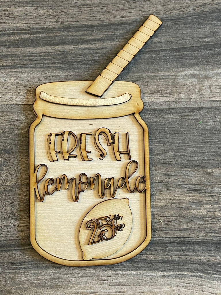 Wooden plaque shaped like a mason jar from a Lemon Tiered Tray DIY Paint Kit - Farmers Market Wood Blanks - U-Pick- Summer Paint Kit, with the words &quot;Fresh Lemonade&quot; and &quot;25¢&quot; carved out, accompanied by a wooden straw, against a gray wood background.