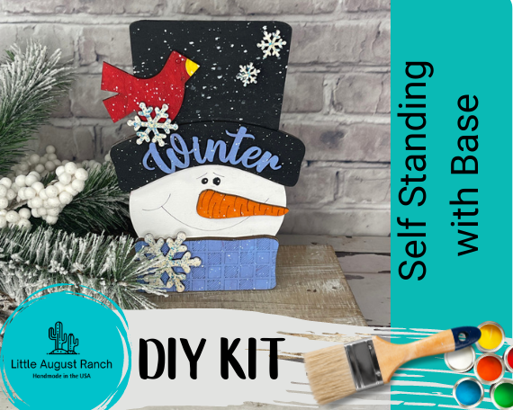 A Chunky Snowman Face DIY Paint Kit from Little August Ranch, perfect for your winter DIY project. This kit includes a snowman standing on a base and is ready to be painted and decorated. Get creative with this wooden Winter Wood Blank - DIY Shelf Decor.