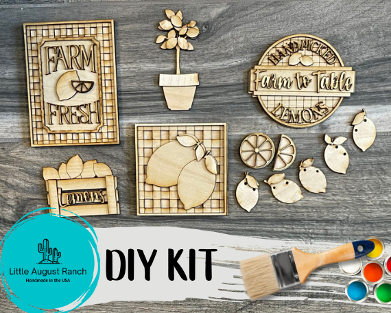 DIY wooden craft kit featuring farm-themed cutouts such as "Farm Fresh," fruits, and vegetables, displayed on a Lemon Tiered Tray with a paintbrush and paint pots. - Farmers Market Wood Blanks - U-Pick- Summer Paint Kit - Summer Wood Blanks by Little August Ranch.