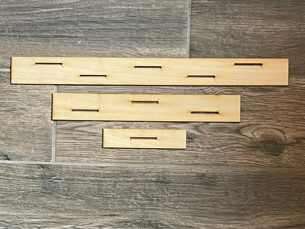 A set of DIY Little August Ranch wooden shelf brackets on a wooden floor.