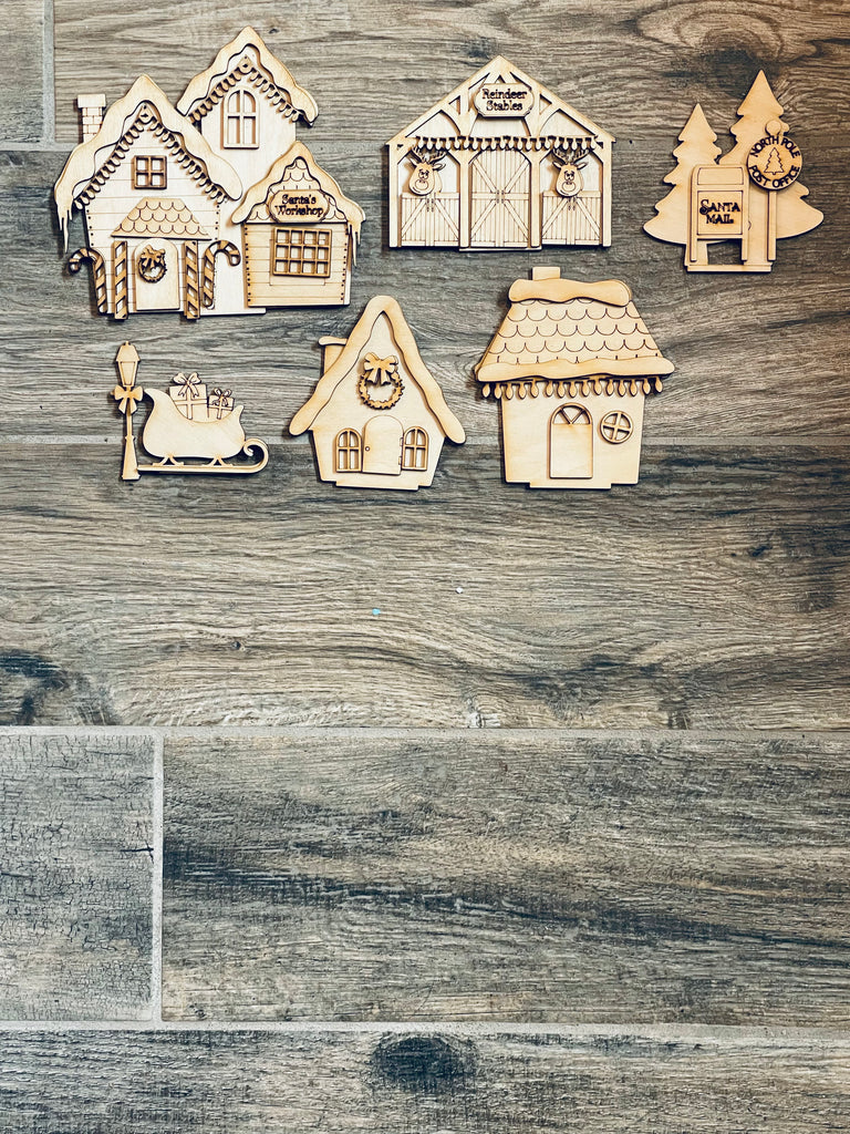 A set of Little August Ranch DIY Christmas Santas Village Standing Pieces - Winter Village - Christmas Shelf Decor Blank Kit - Reindeer Barn, Sleigh, Santa Mailbox Blank wooden gingerbread houses.