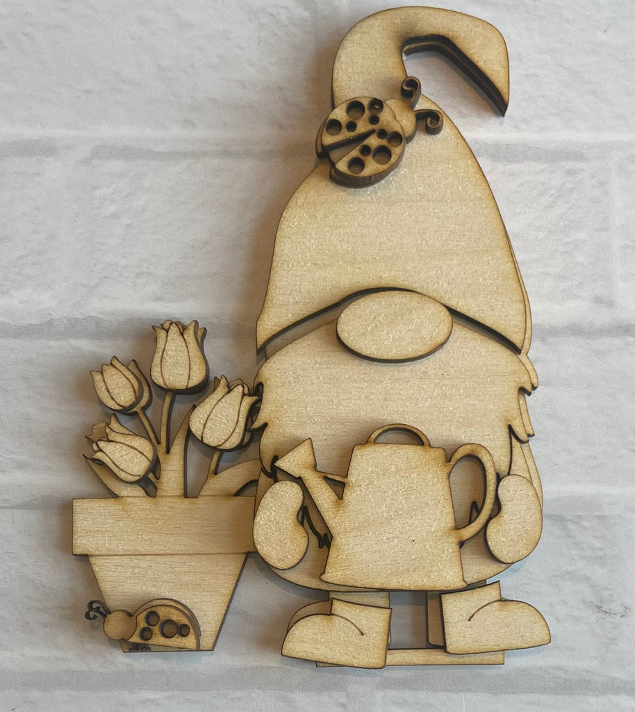 A wooden gnome with a pot of flowers, part of the Little August Ranch Spring Gnome Standing Gnome Kit - Tiered Tray Gnome - Paint it Yourself - DIY Spring. This self-standing wood kit allows for DIY paint and decorate fun.