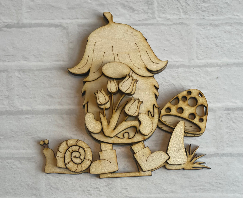A Little August Ranch Spring Gnome Standing Gnome Kit featuring a wooden cut out of a gnome, adorned with flowers and snails. This self-standing wood kit allows for DIY paint and decorate opportunities.