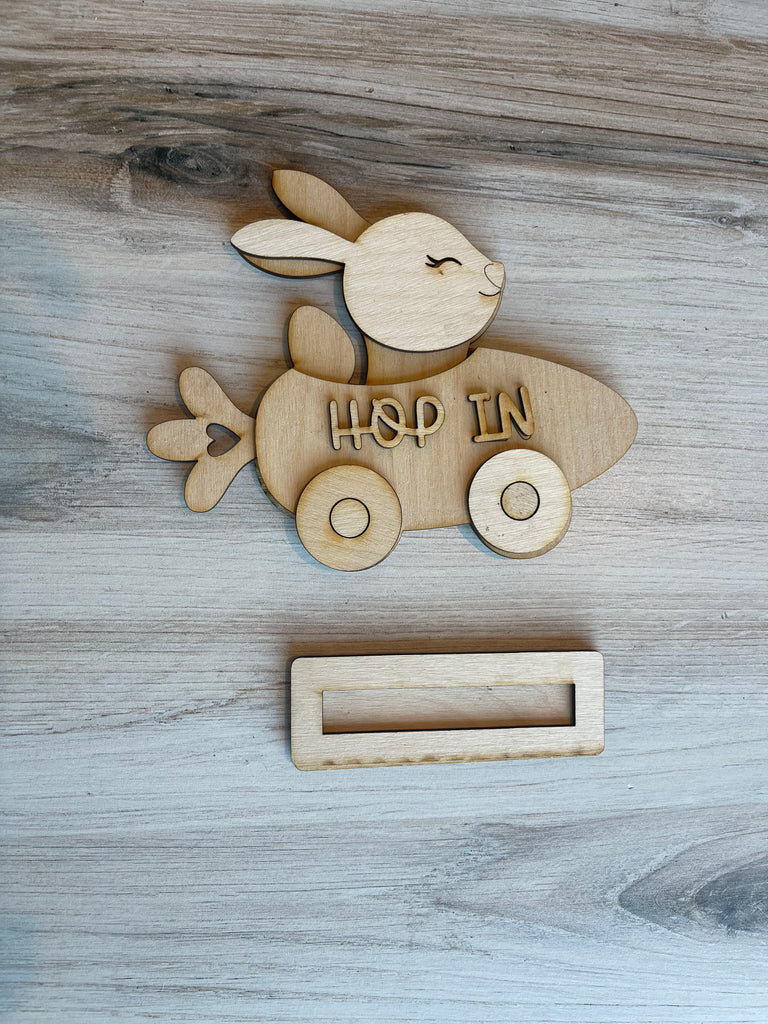 A Little August Ranch DIY wood paint kit featuring a Carrot Car and Flower Holder Spring Bunny in a rocket on a table.