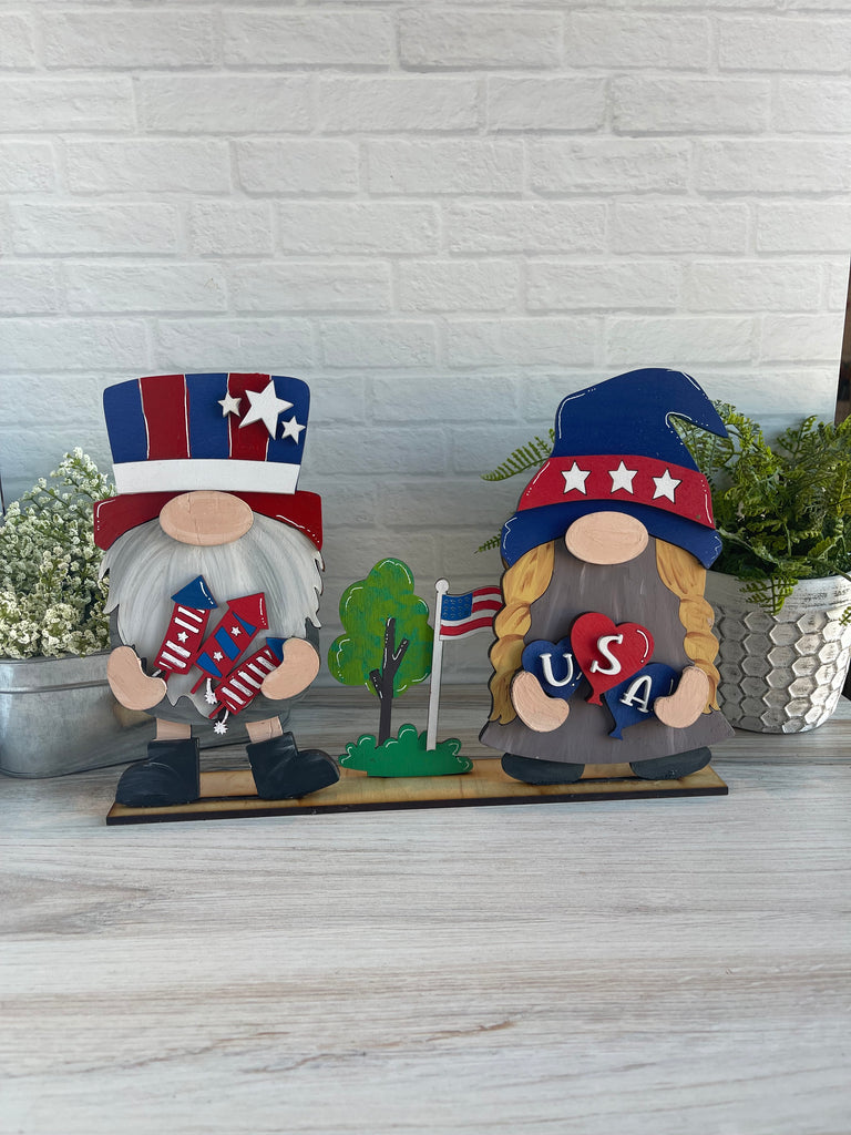 Two Little August Ranch DIY gnome pair wearing 4th of July Freestanding Wood Gnome Outfits- Patriotic Interchangeable Gnomes - DIY Paint and Decorate Yourself inserts with American flags on their heads.
