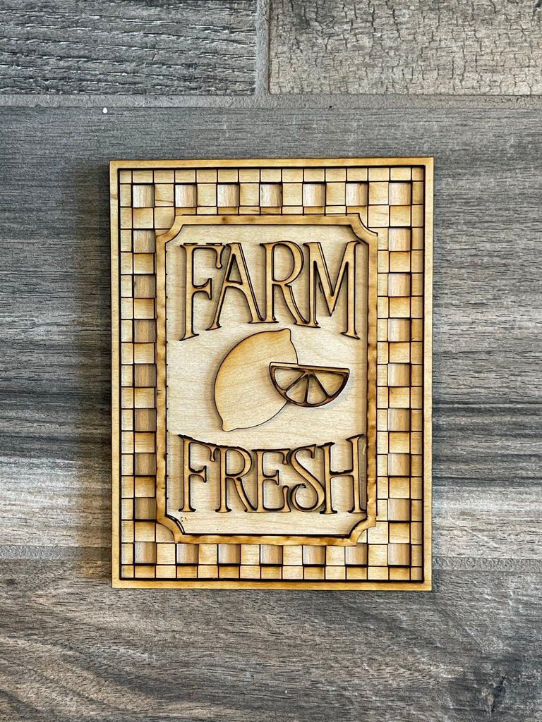 A Lemon Tiered Tray DIY Paint Kit with the words "FARM FRESH" carved into it, featuring a stylized egg design in the center, placed on a grey wooden surface from our Little August Ranch Farmers Market Wood Blanks.