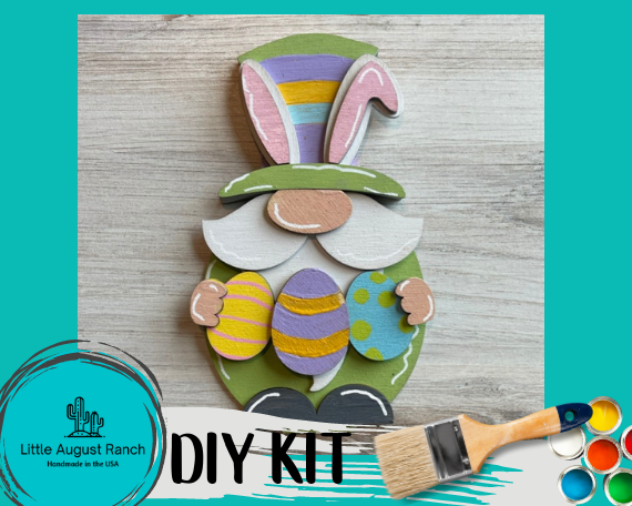 An Easter Bunny Gnome crafted from wood, adorned with bunny ears and holding eggs. The Easter Bunny Gnome with Eggs DIY Wood Paint Kit- Standing Gnome on Base - DIY Paint Kit by Little August Ranch.
