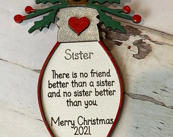This personalized Sister Christmas Ornament from Little August Ranch features a charming holly topper and the heartfelt message "there is no friend better than a sister.