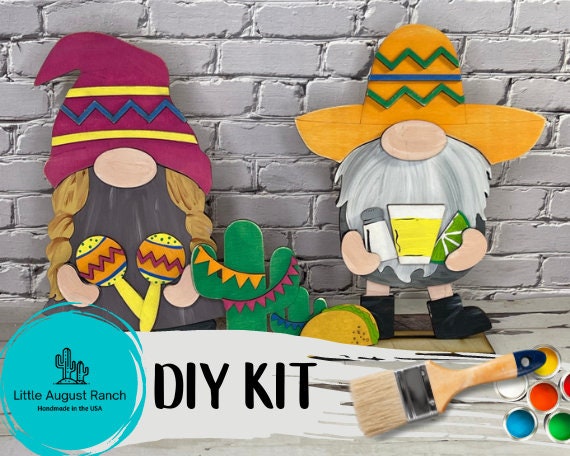 A DIY kit with two Fiesta Freestanding Wood Gnome Outfits- Cinco de Mayo Interchangeable Gnomes and a paint brush by Little August Ranch.