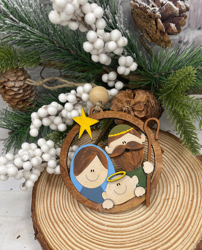A hand-painted Little August Ranch Nativity Christmas ornament on a tree.
