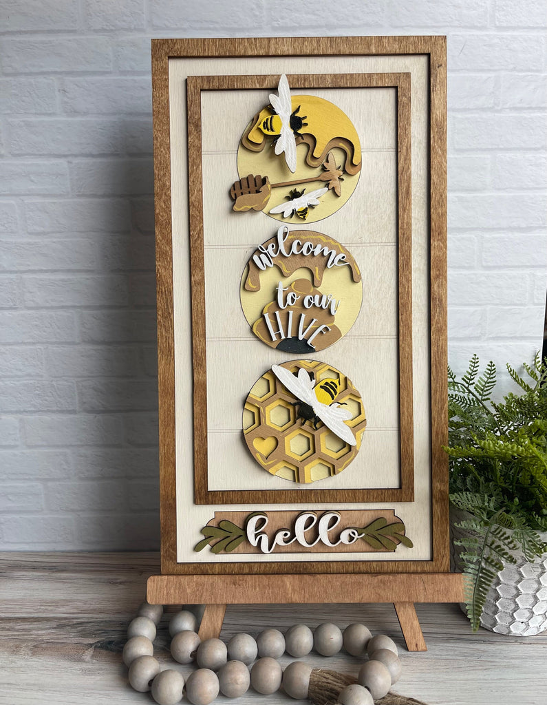 A wooden frame with a honey bee and an interchangeable beehive decor on it from Little August Ranch's Bee Circle Trio DIY Wood Paint Kit for 3 Circle Frame.